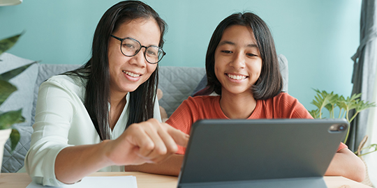 Asian family with a daughter do homework by using tablet with mother help. Happy smile Asia kid while sitting in the living room at home morning. Concept of online learning at home